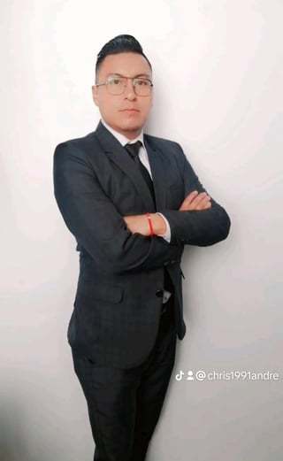 Man in dark business suit and glasses standing with arms crossed against white wall